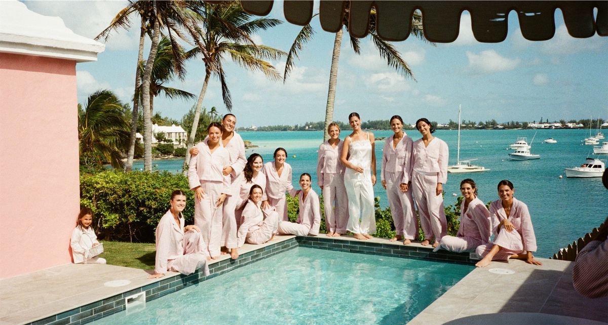 Bridesmaids in pink posed around a swimming pool overlooking the harbour