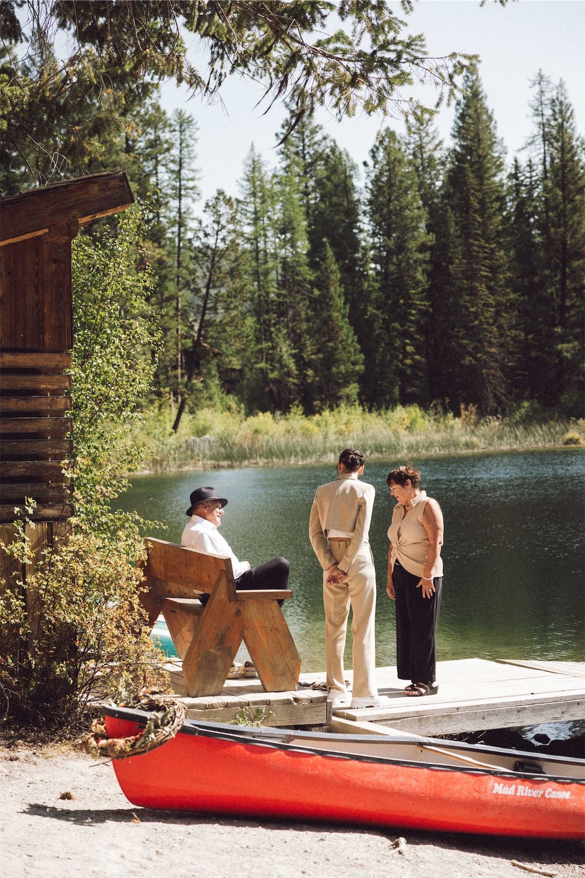 Couple standing on the dock beside a red canoe at the lake edge