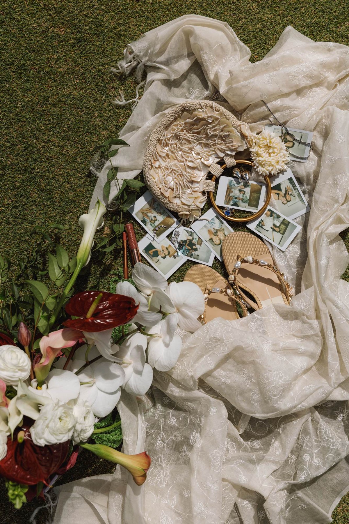 Flat lay of the wedding flowers, polaroids and invitation on the grass
