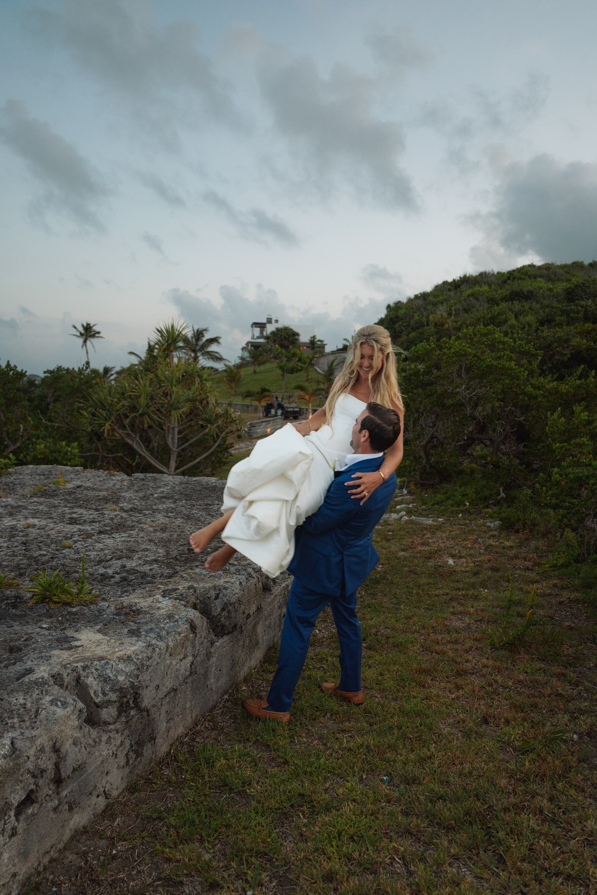 Cam lifts Paige on the old stone wall at dusk on Hawkins Island, Bermuda