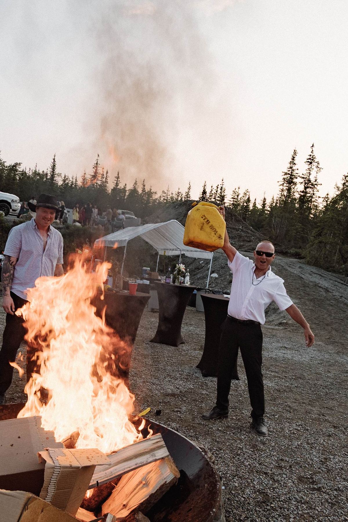 Guests gathered around a bonfire at dusk after a mountaintop wedding