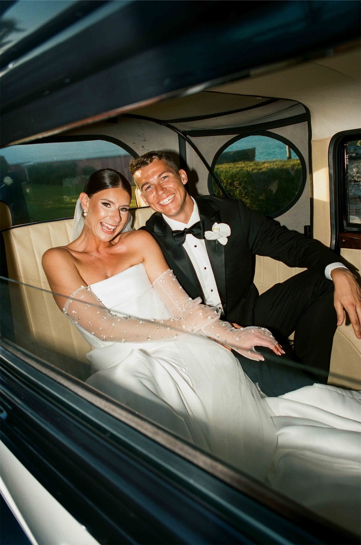 Newlyweds riding together in the back seat of a vintage car