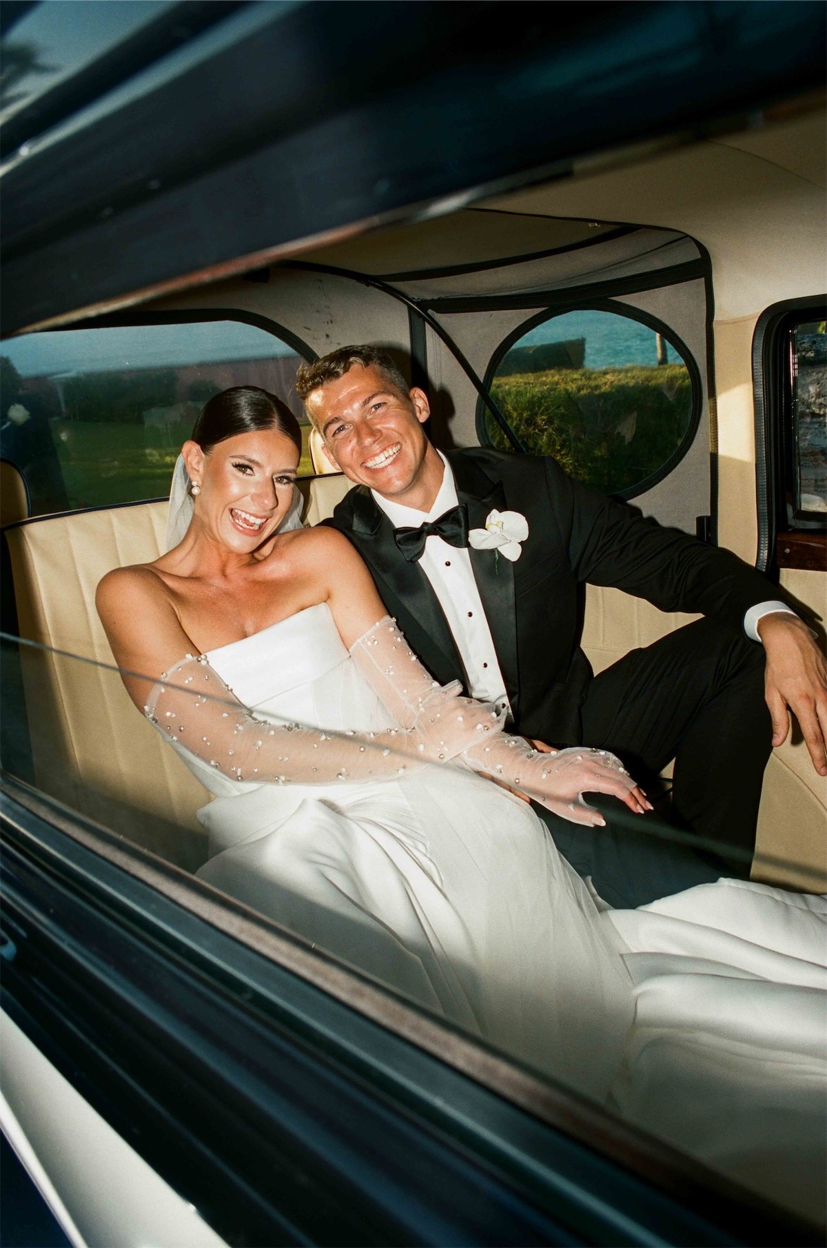 Newlyweds riding together in the back seat of a vintage car