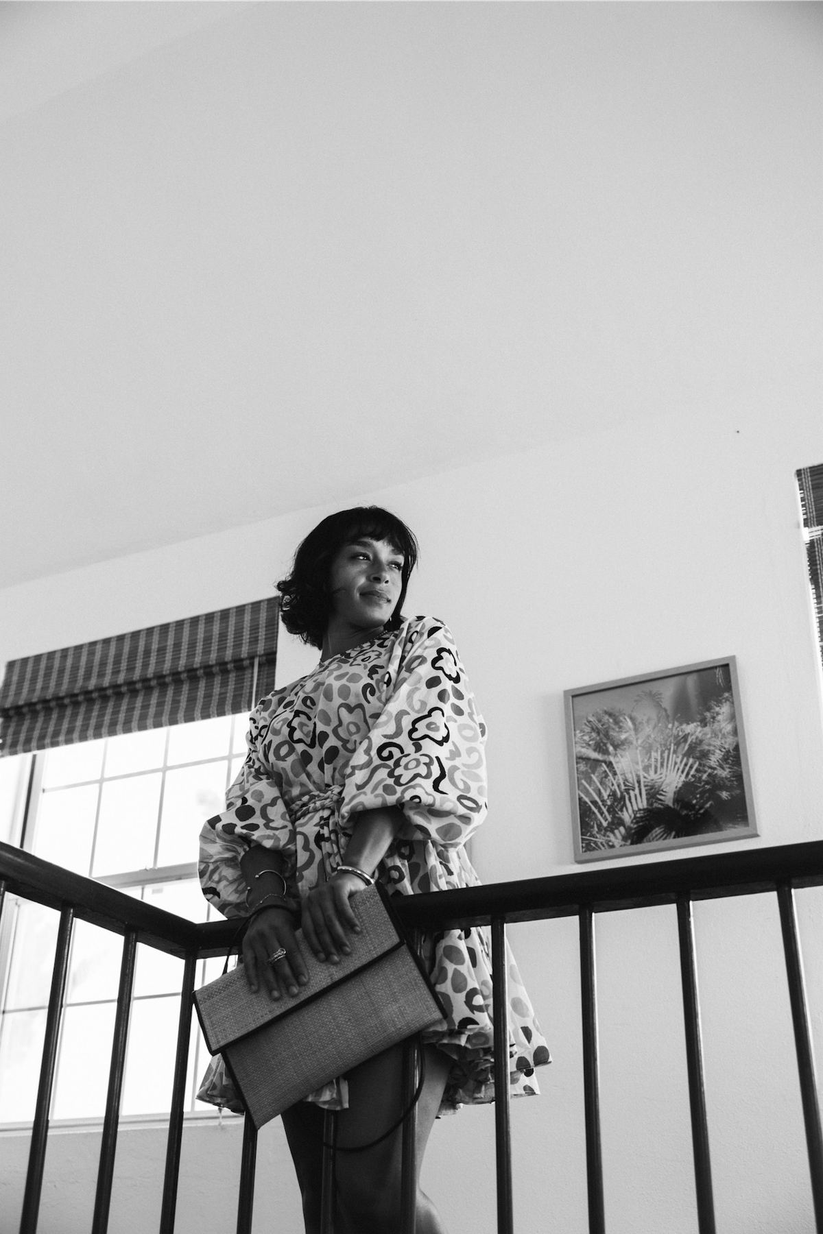 Black and white of a model carrying a tote bag down an interior staircase