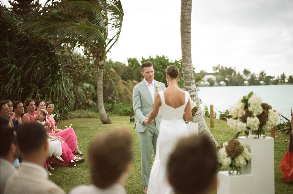 Bride and groom facing each other during the lawn ceremony as guests look on