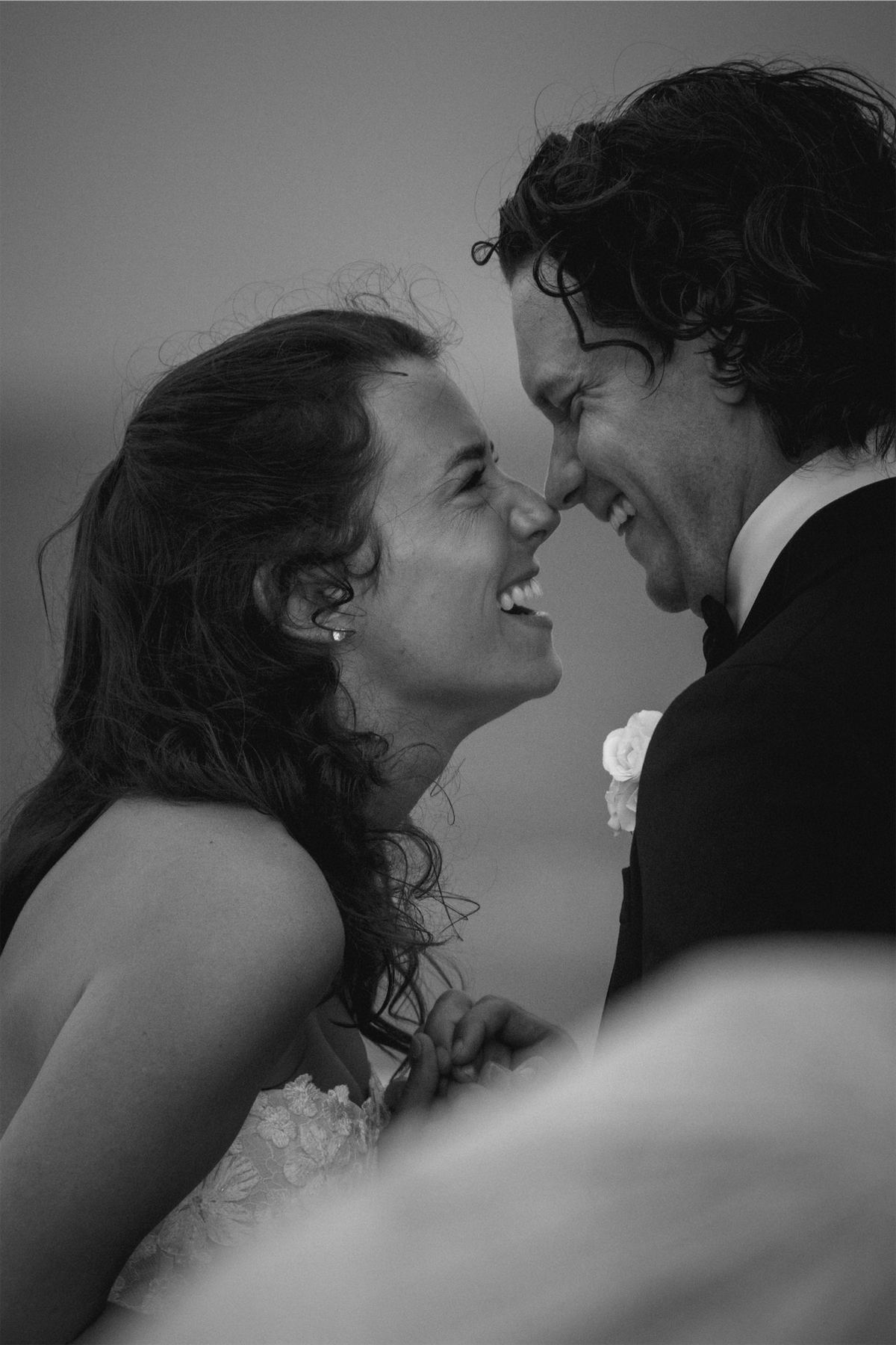 Black and white portrait of the bride and groom laughing nose to nose