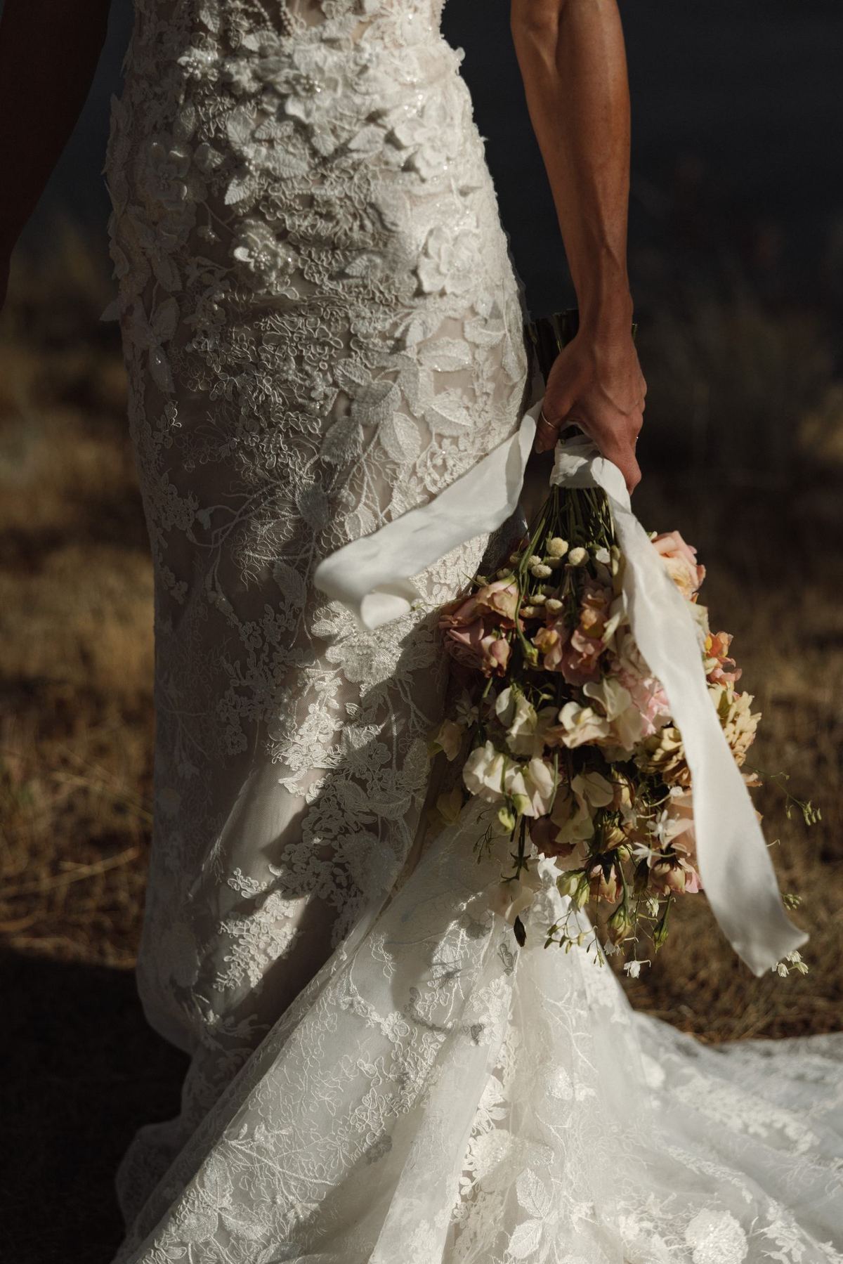 Bouquet held at the bride's side against the texture of her lace gown
