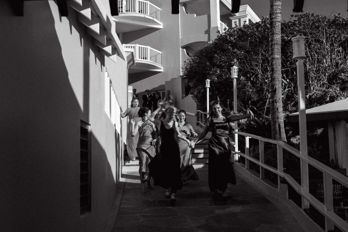 Black and white photograph of bridesmaids running down stairs at Bermuda wedding