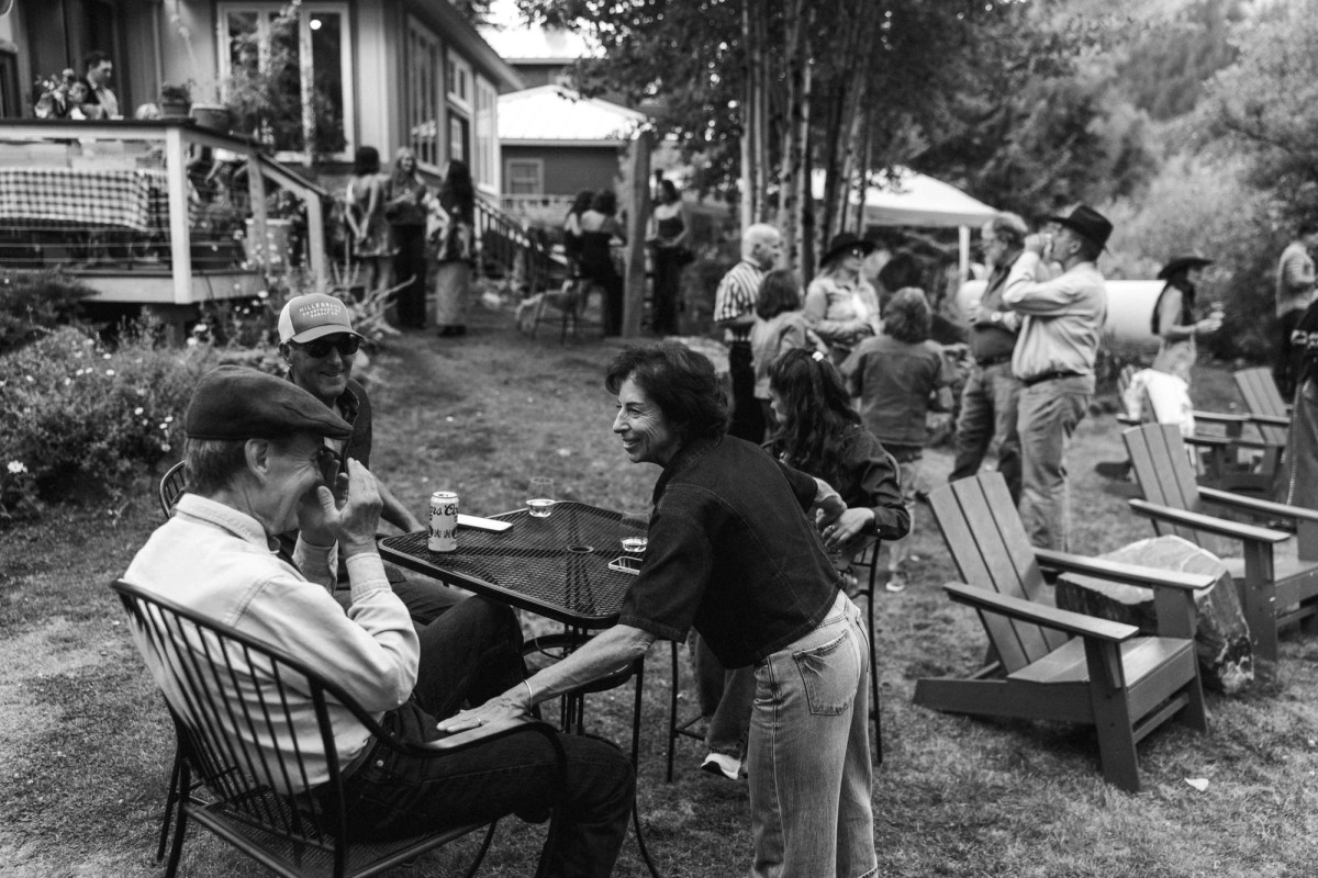 Guests catch up in the garden at the welcome dinner at a mountain ranch among the aspens, black and white