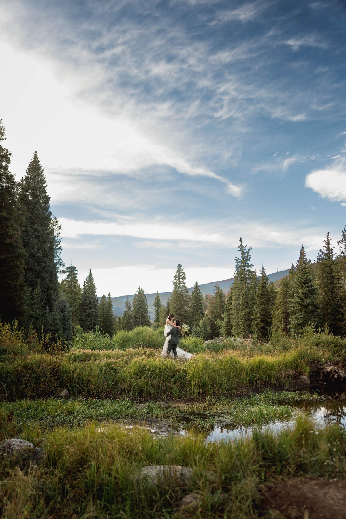 Devin and Owen small in the meadow under a big mountain sky at a mountain ranch among the aspens