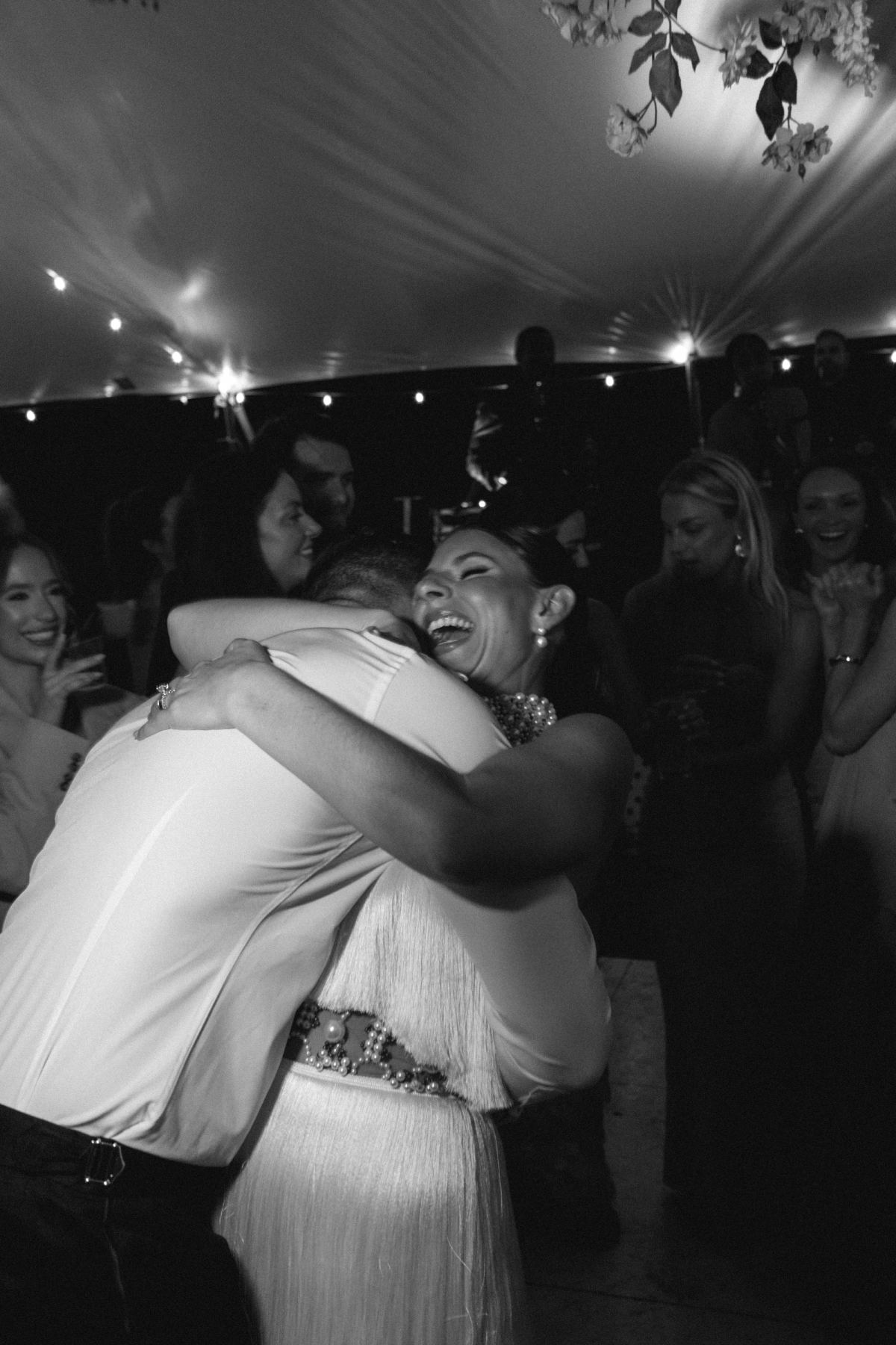Black and white embrace on the dance floor beneath the reception tent