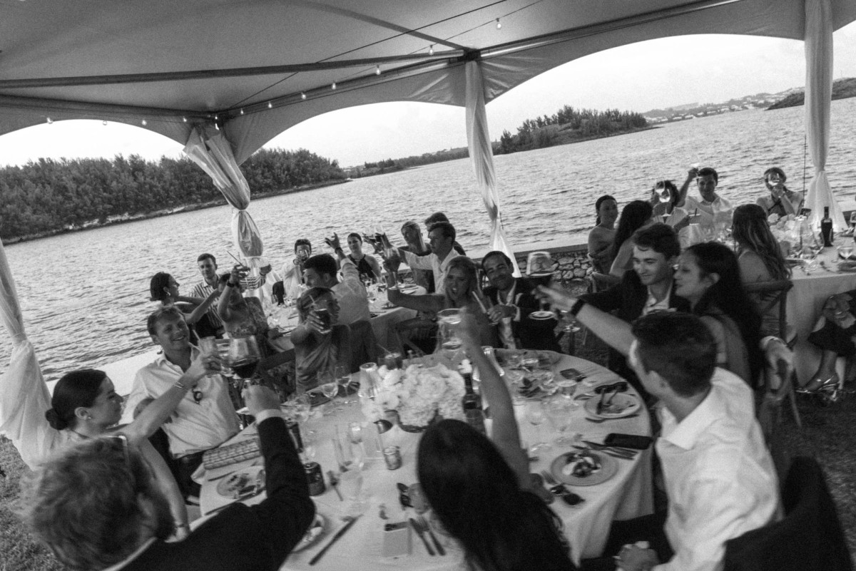 The whole tent raises a toast over dinner on Hawkins Island, Bermuda, black and white