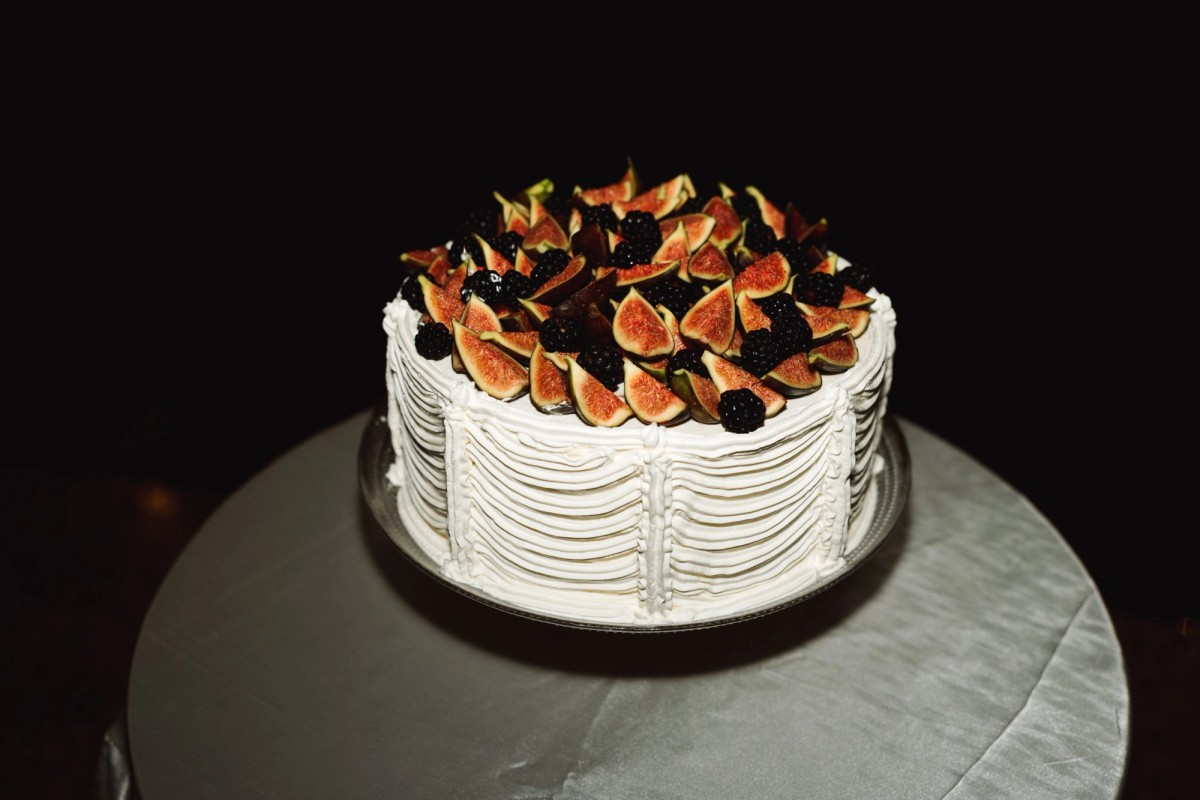 Wedding cake topped with figs and blackberries under a spotlight at Rosewood Bermuda