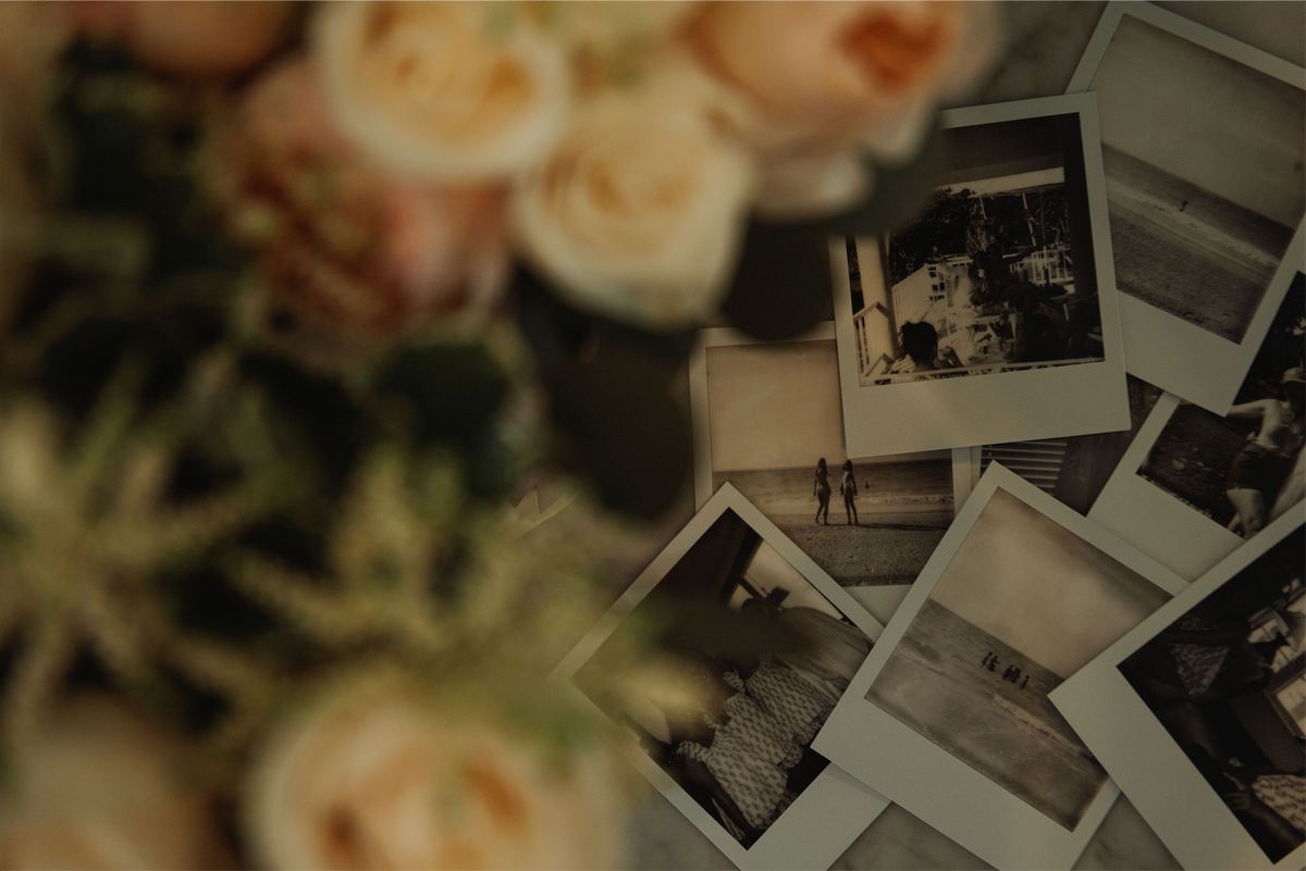 Polaroid guest photos scattered beside peach garden roses on a table