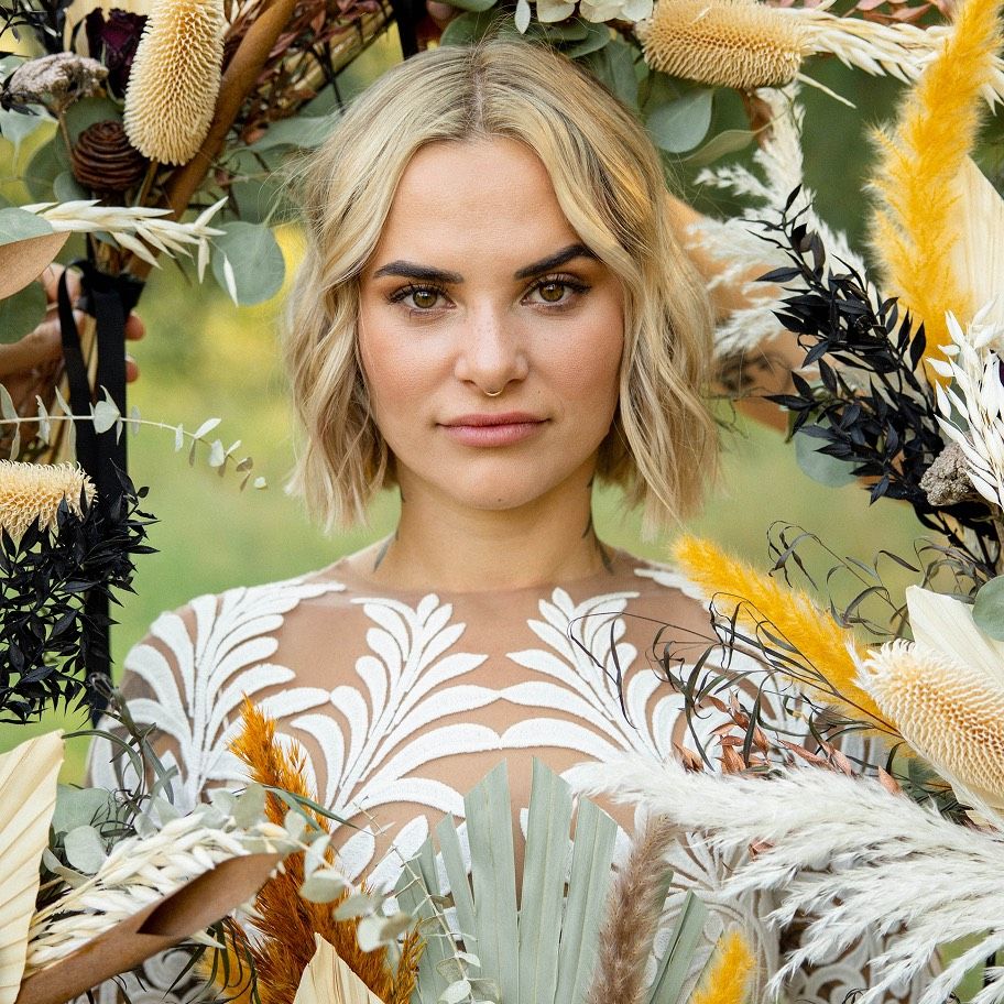 Bride framed by dried pampas and wildflowers in an ornate lace gown