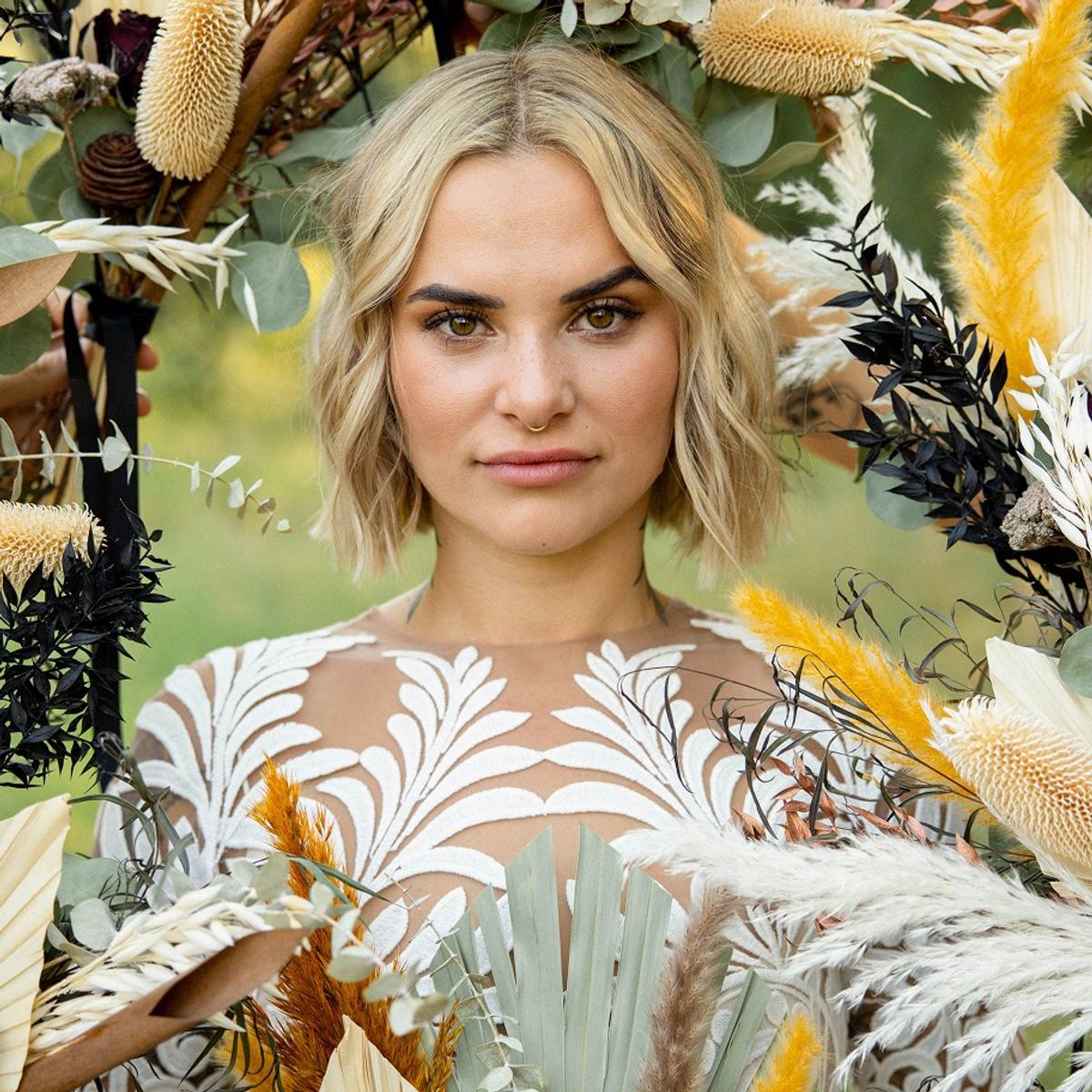 Bride framed by dried pampas and wildflowers in an ornate lace gown