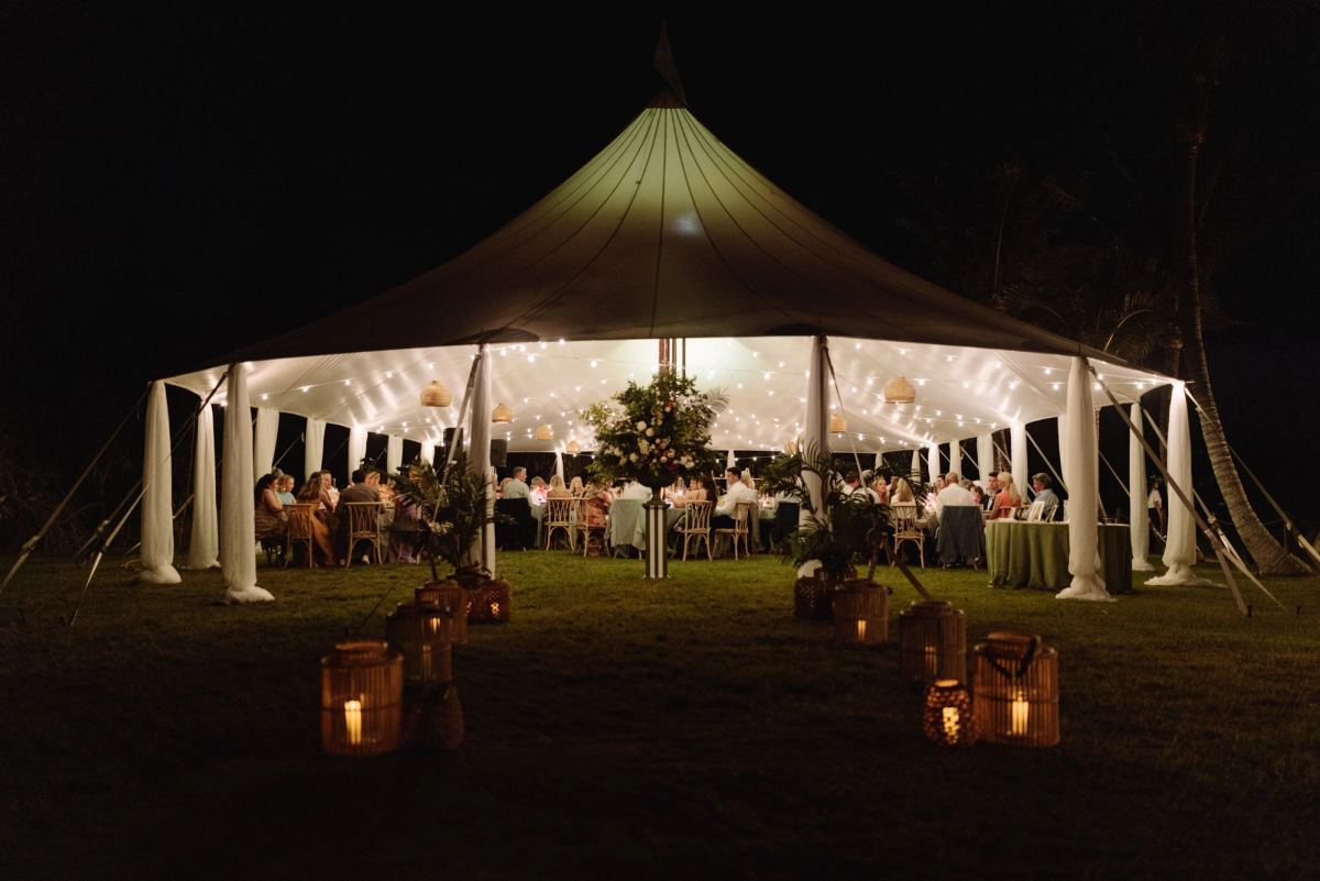 Sailcloth tent glowing with lanterns on the lawn at night