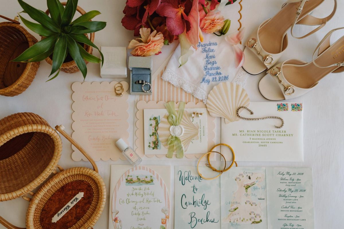 Flat lay of the wedding invitation suite, heels and tropical flowers