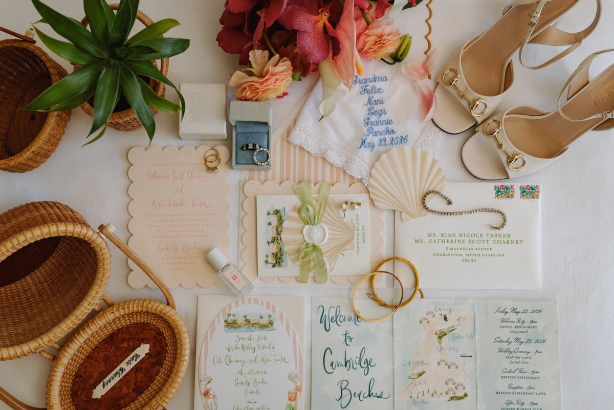 Flat lay of the wedding invitation suite, heels and tropical flowers
