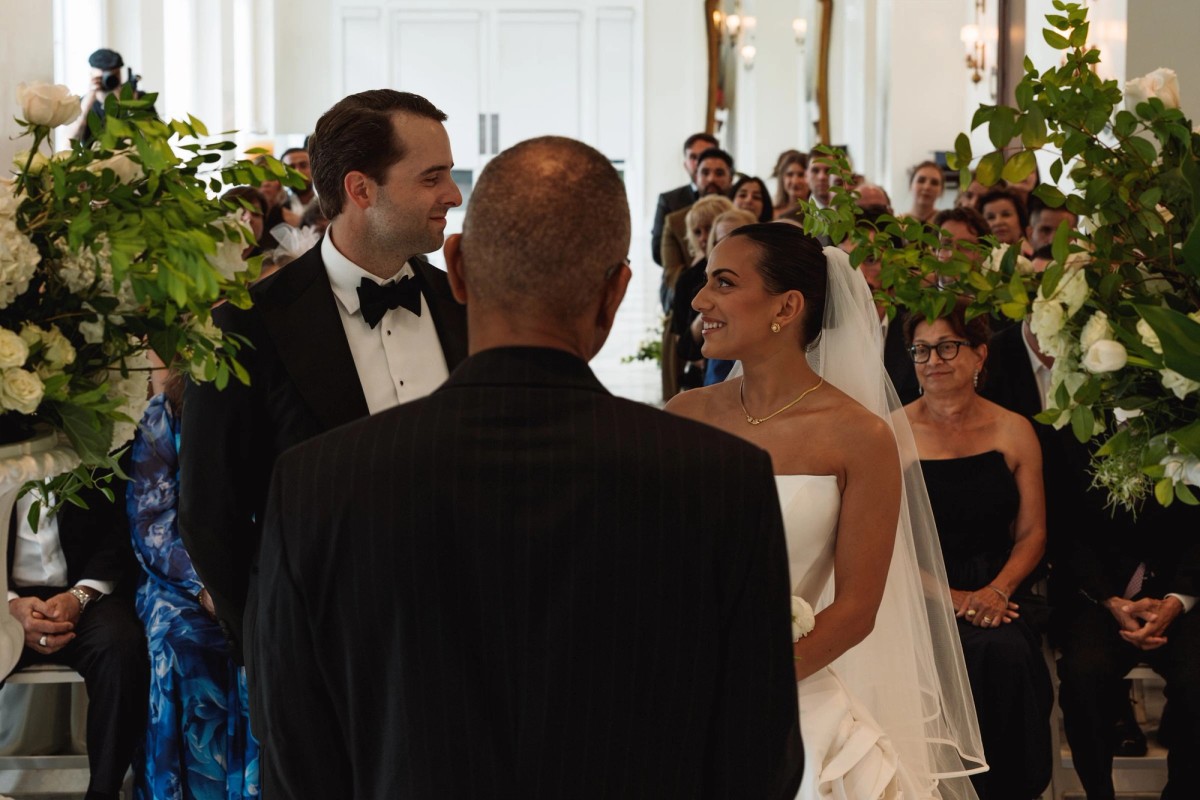 Couple sharing a smile at the altar framed by white florals at Rosewood Bermuda