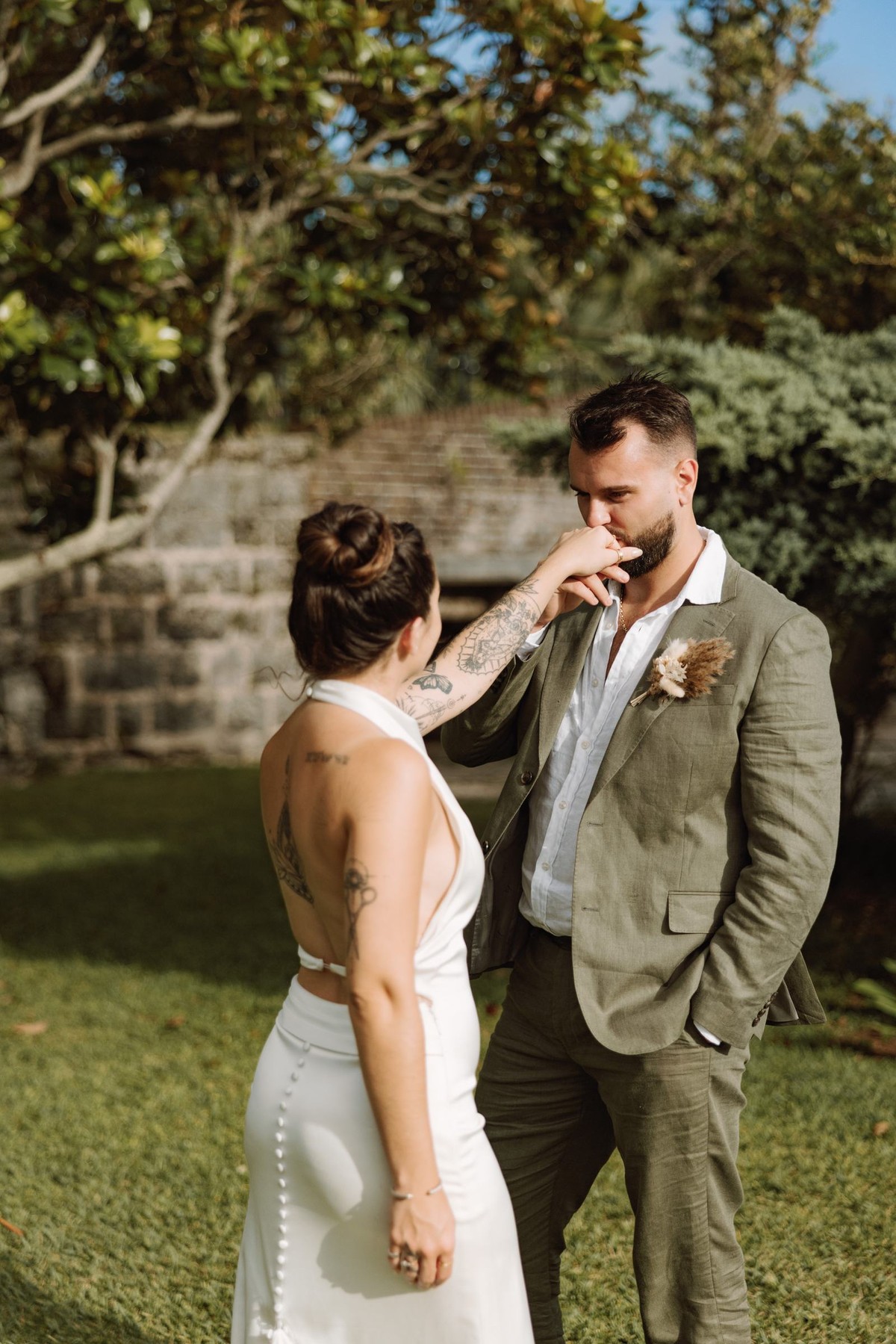 Groom kissing the bride's hand on the lawn after their ceremony