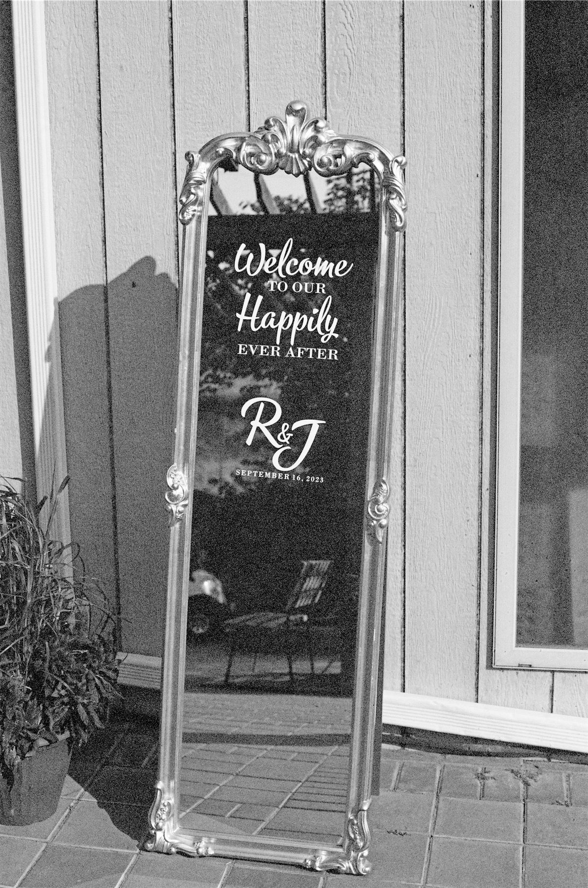 Black and white of an ornate mirrored welcome sign at the venue entrance