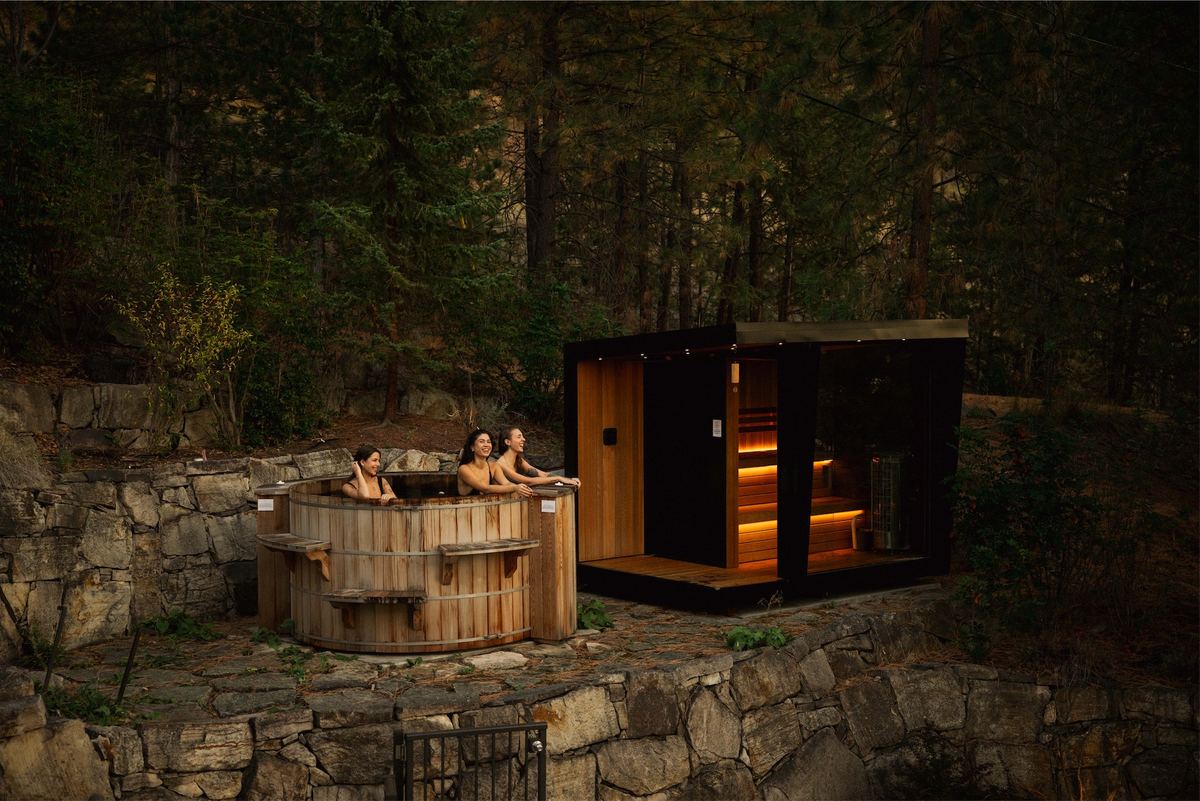 Cedar hot tub and modern sauna cabin built into a rocky forest hillside