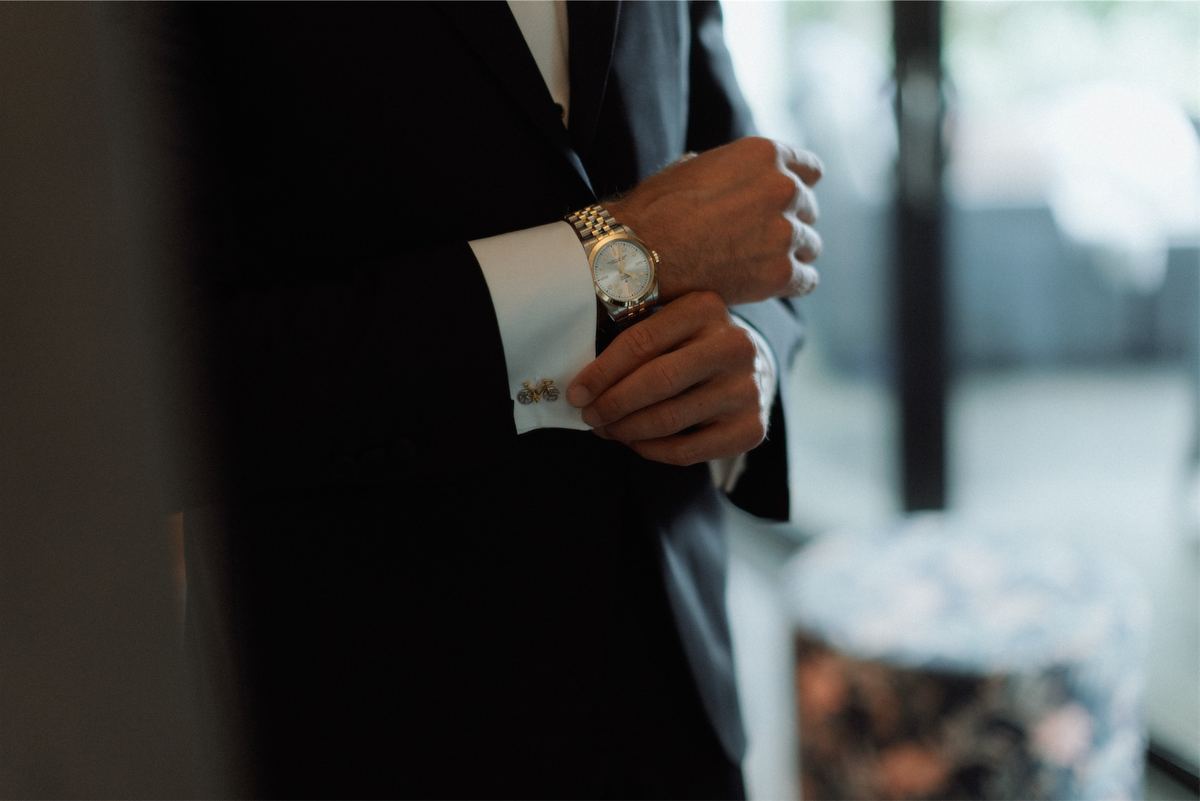 Close detail of the groom adjusting his cuff and gold watch before the ceremony