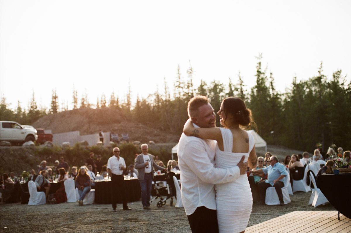 Bride and groom dancing at golden hour with guests and the valley behind them