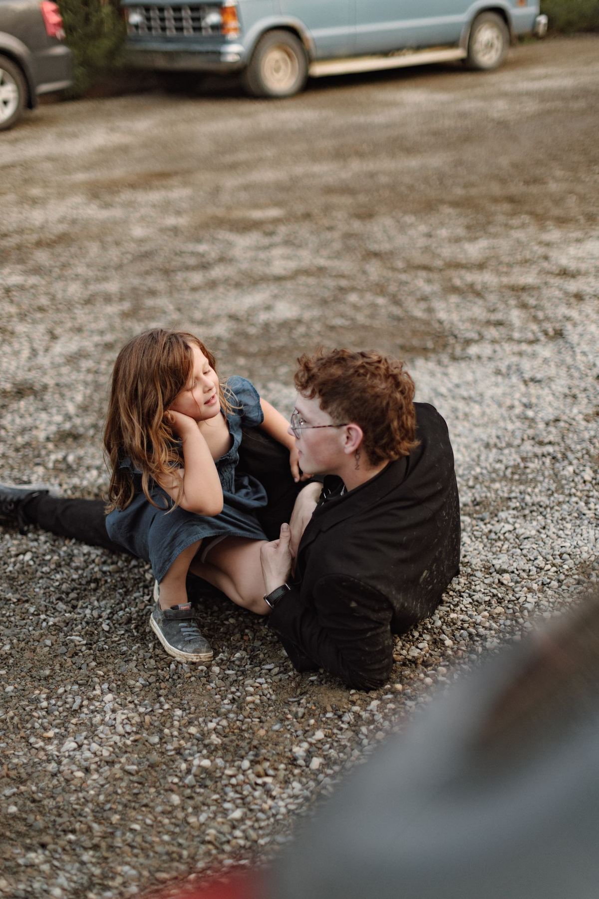 Two children lying on the gravel laughing during the wedding party