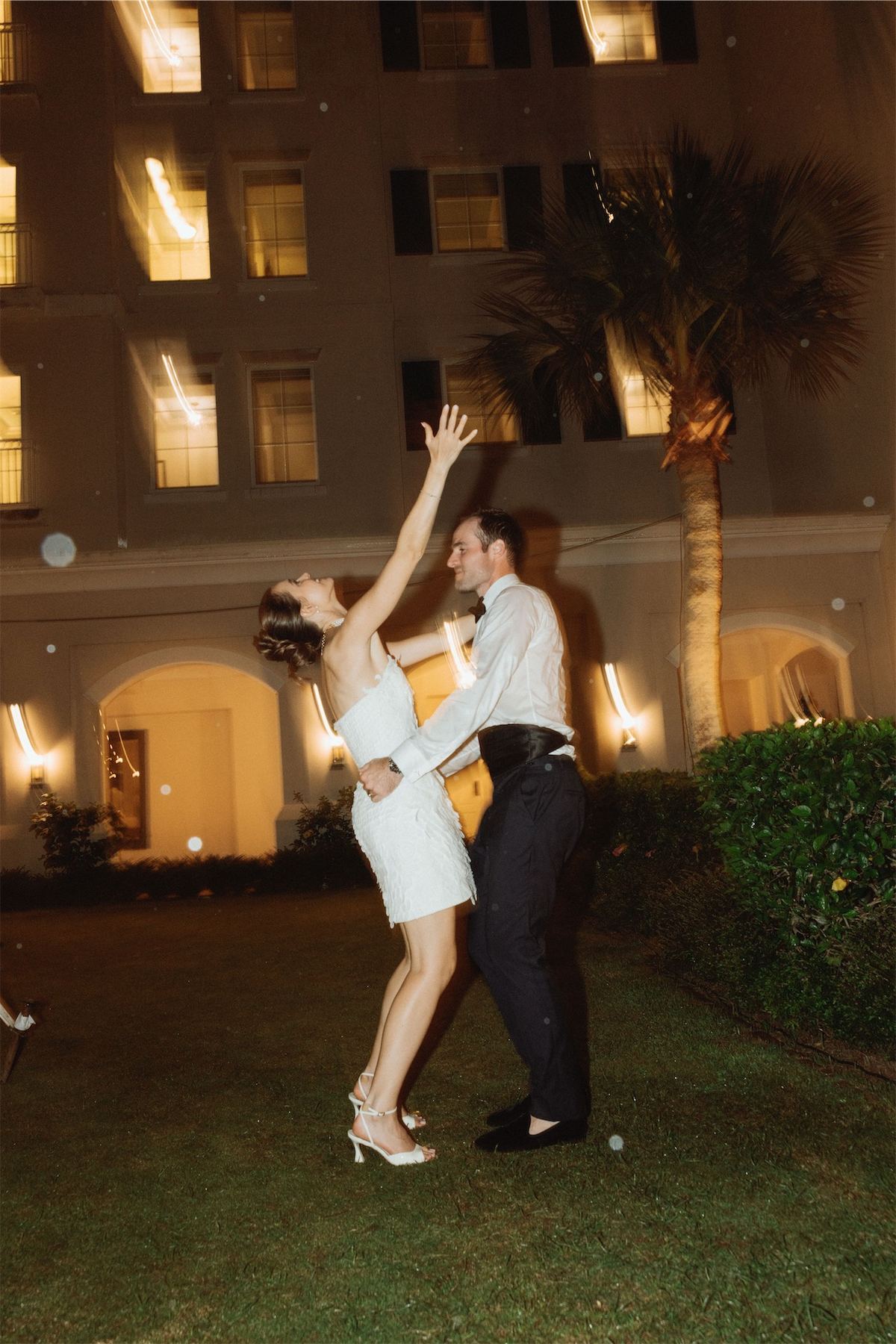 Couple dancing outside the lit hotel facade late at night