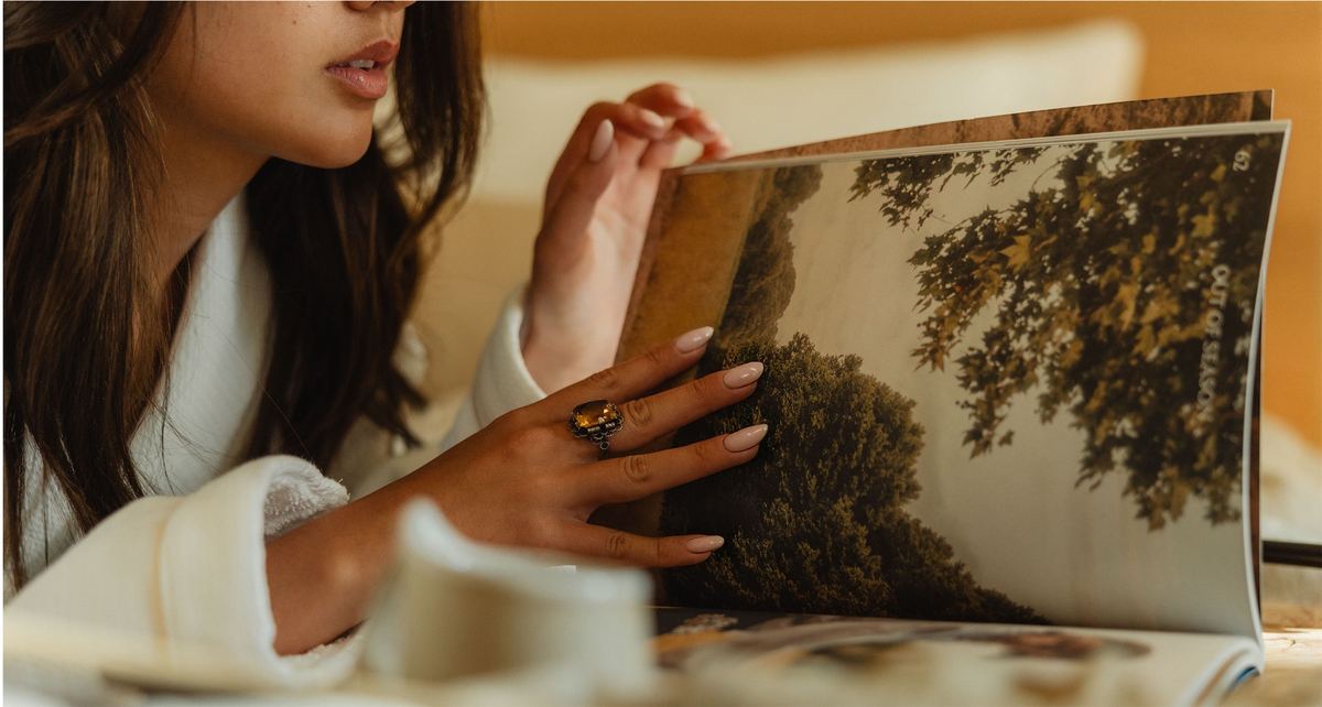 Woman in a robe turning the pages of a large photography book