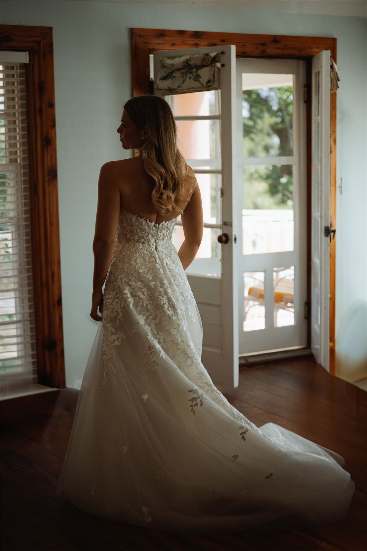 Bride in her lace gown standing in an open doorway before the ceremony