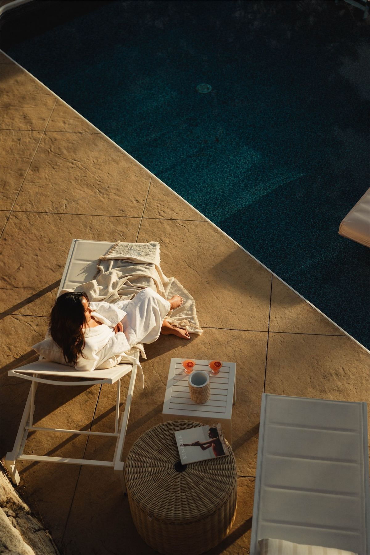 Overhead of a woman resting on a lounger on the pool terrace