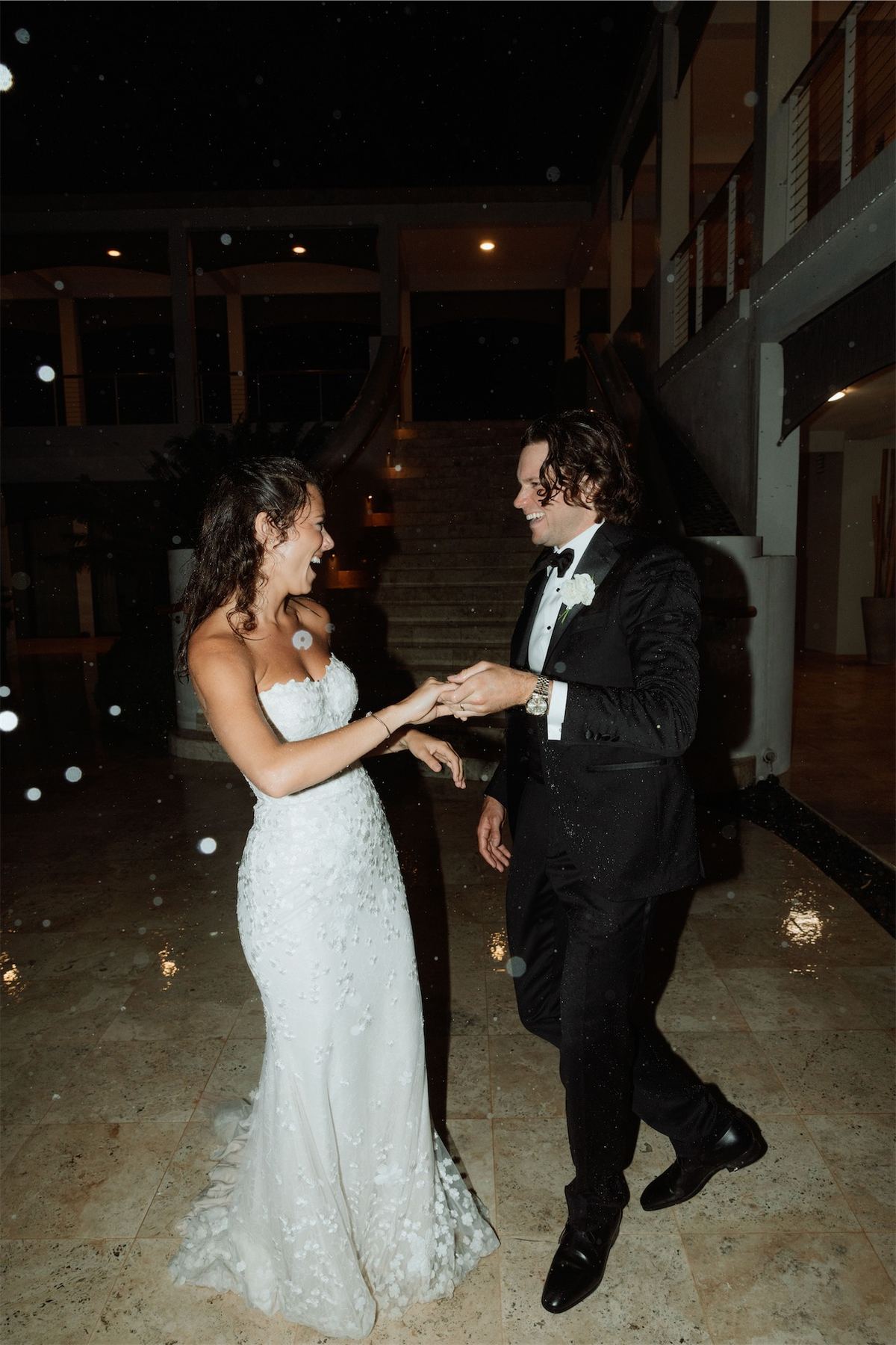 Newlyweds dancing hand in hand across the terrace during the evening reception