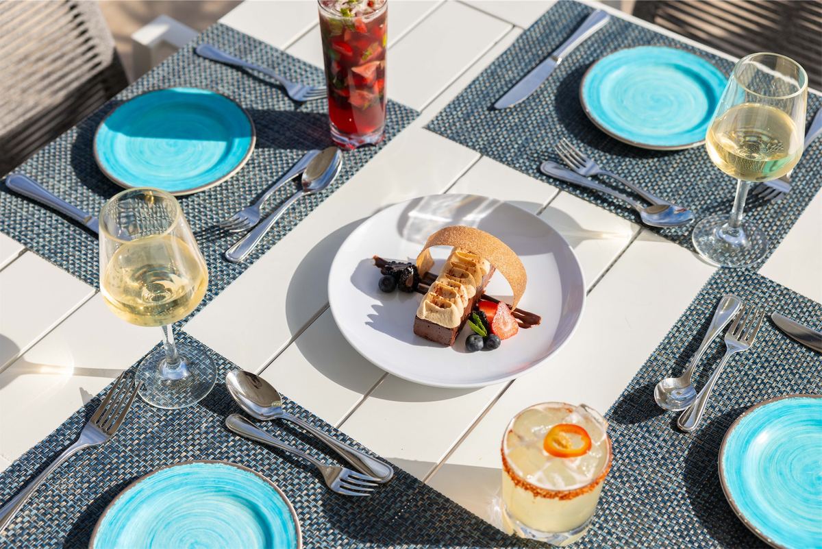 Overhead of a dining table set with turquoise plates, wine glasses and dessert