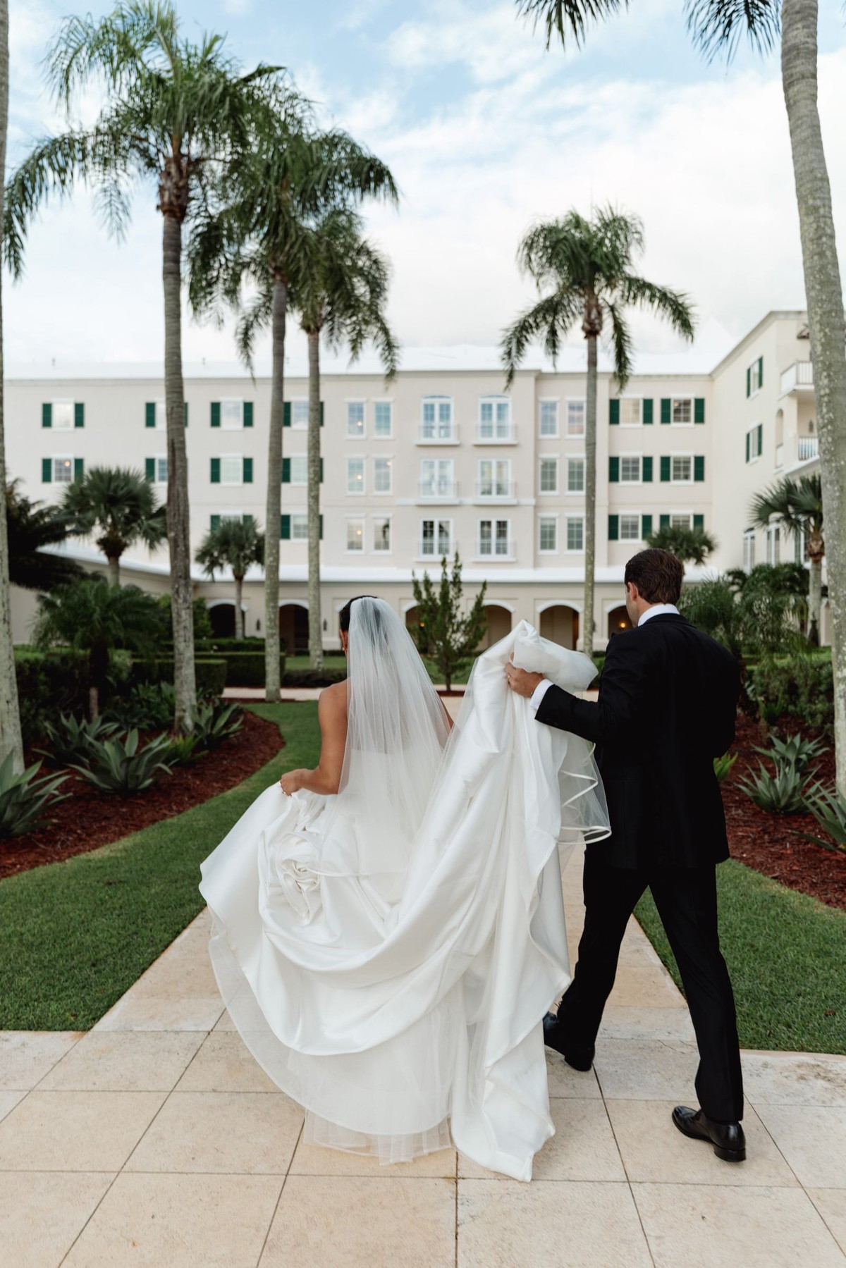 Groom carrying the train as the couple walks toward the hotel at Rosewood Bermuda