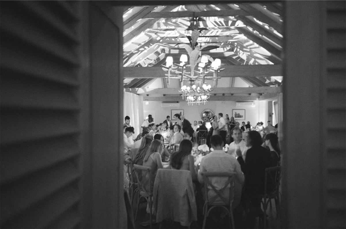 Black and white down the aisle toward guests seated in a timbered hall