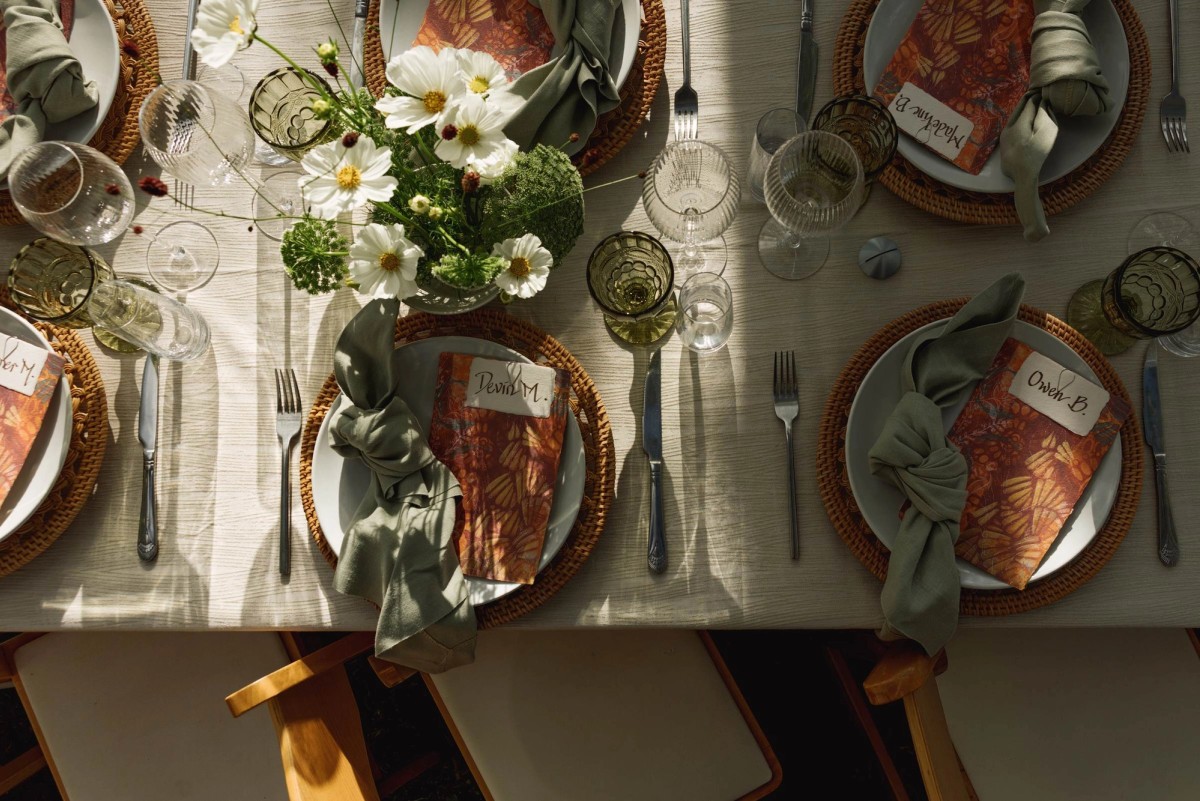Place settings with green napkins, cosmos and amber glassware at a mountain ranch among the aspens
