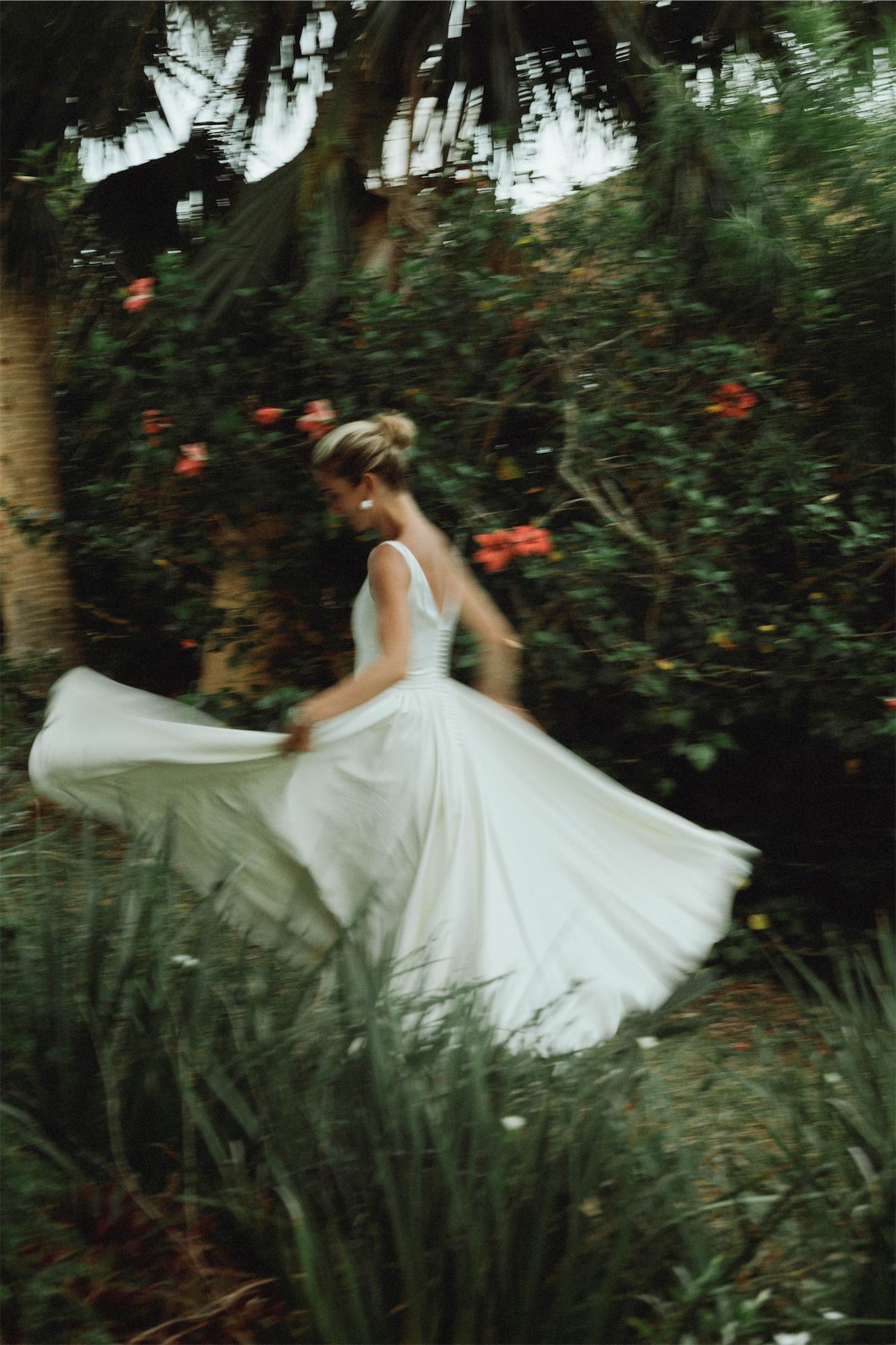 Bride twirling her skirt in a sunlit tropical garden