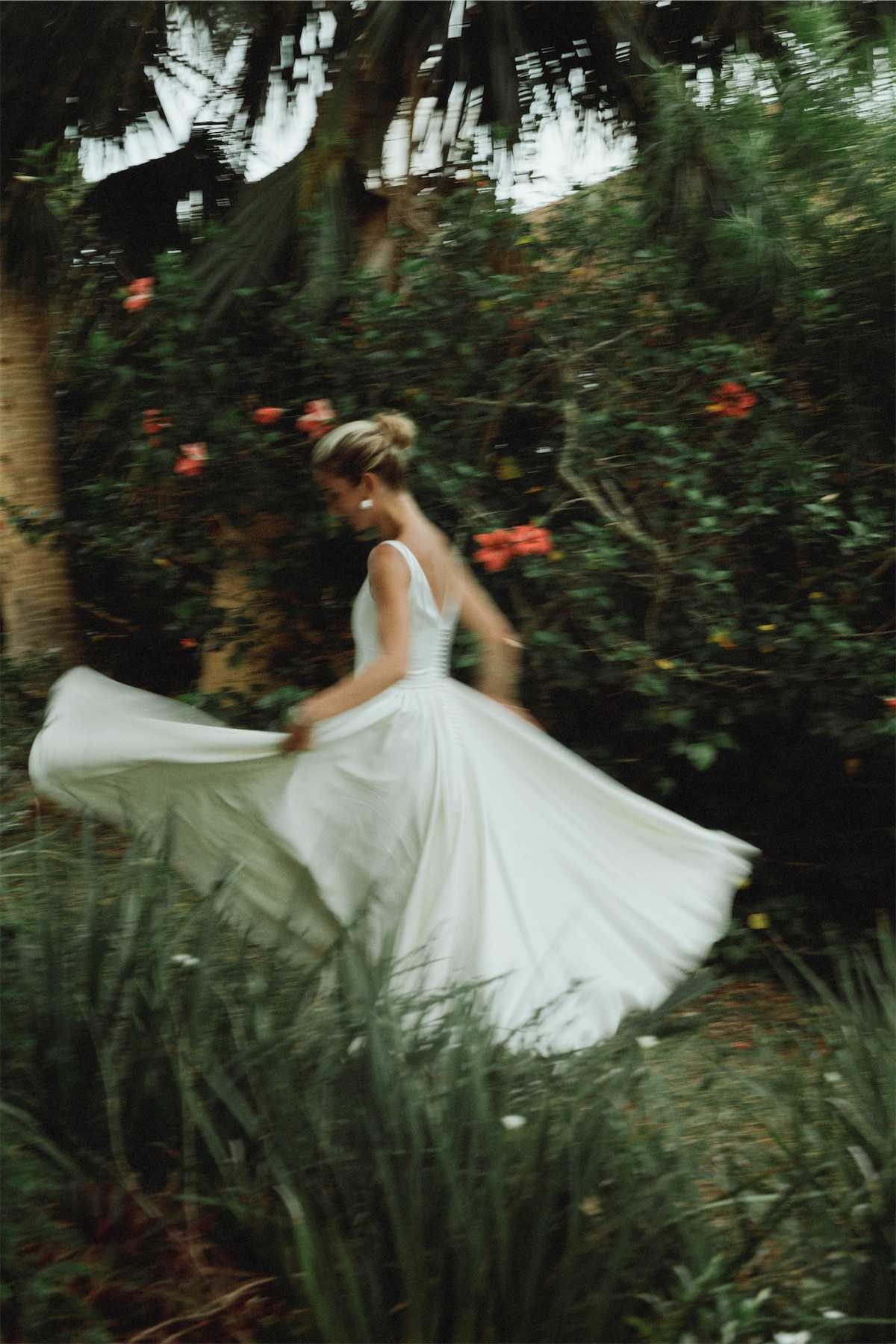 Bride twirling her skirt in a sunlit tropical garden