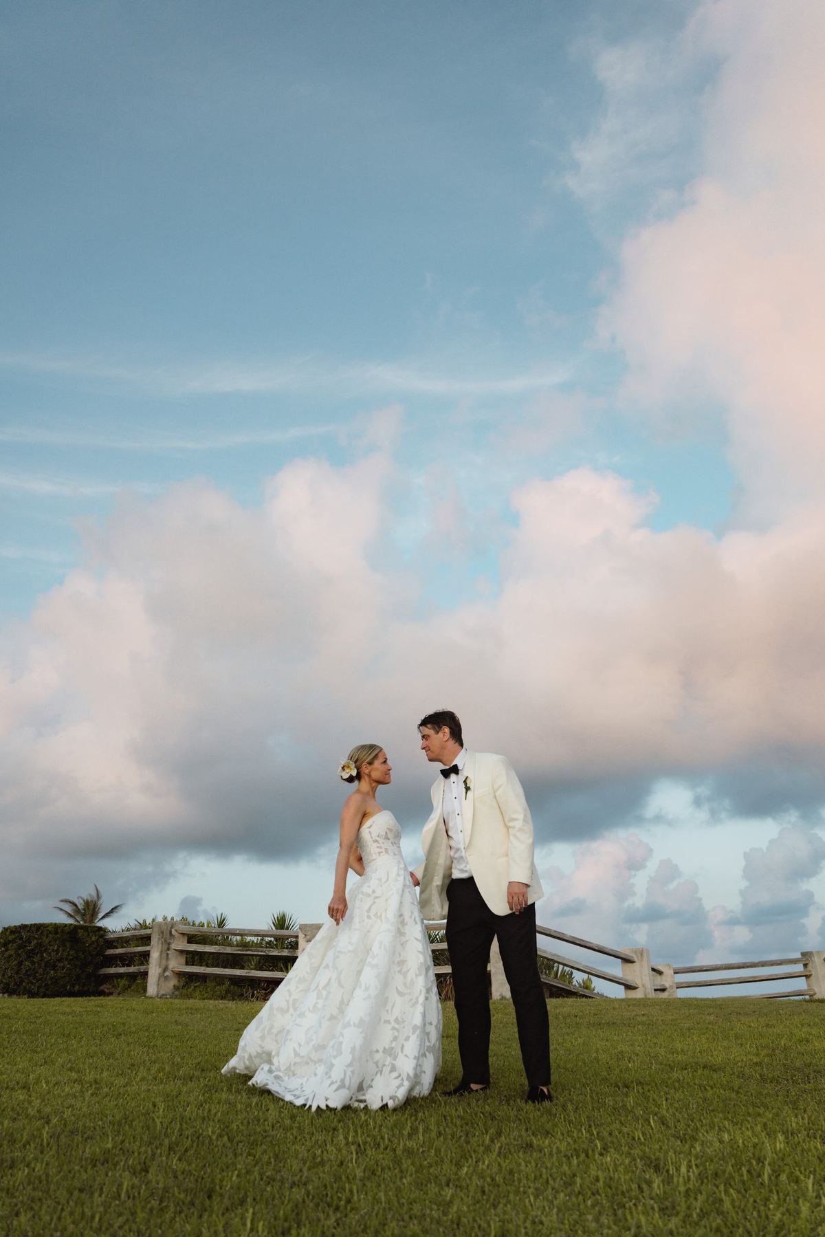 Bride and groom alone on the lawn beneath a wide Bermuda sky