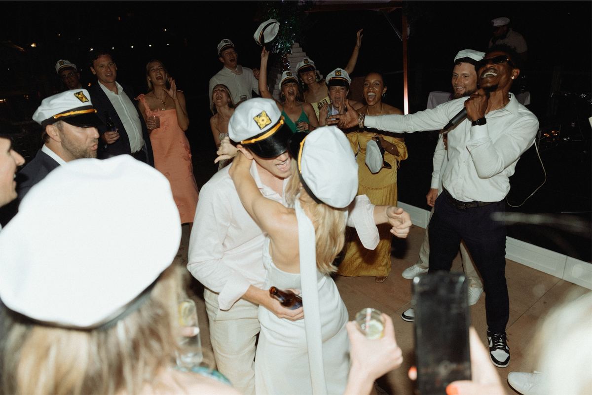 Guests in sailor caps dancing while a singer performs at the reception