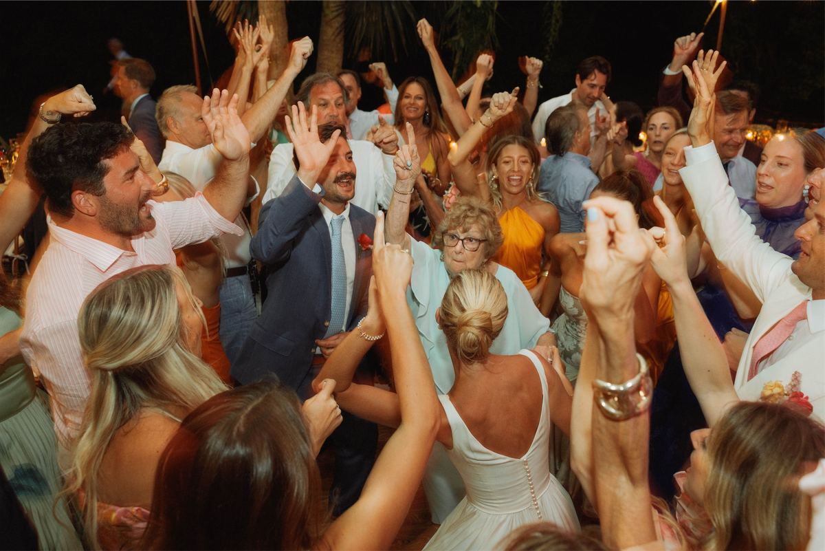 Guests with arms raised dancing around the bride at the reception