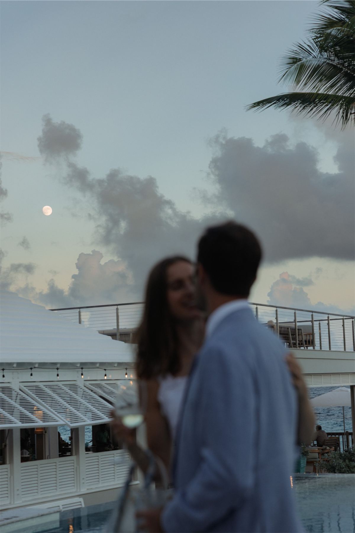 Couple embracing at dusk as the moon rises through the clouds