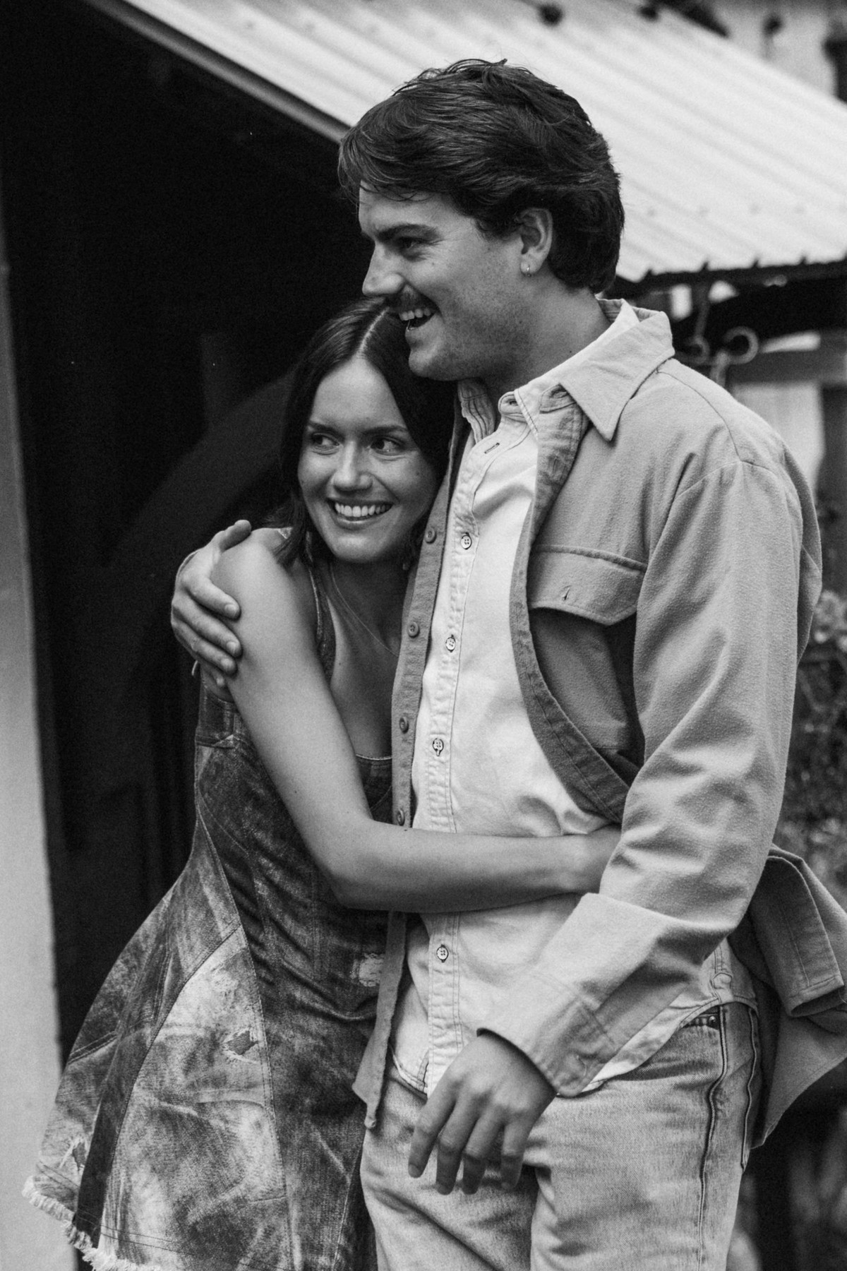 Devin and Owen laugh together in the doorway at a mountain ranch among the aspens, black and white