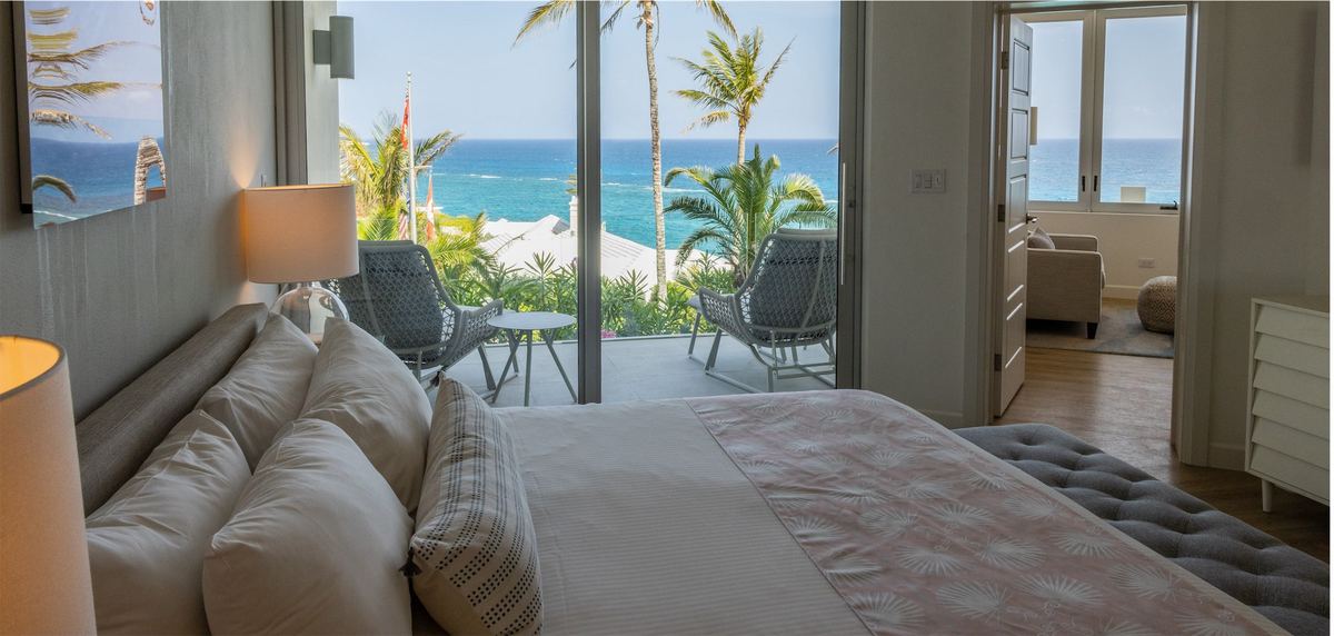 Resort bedroom opening through sliding doors onto a balcony over the sea