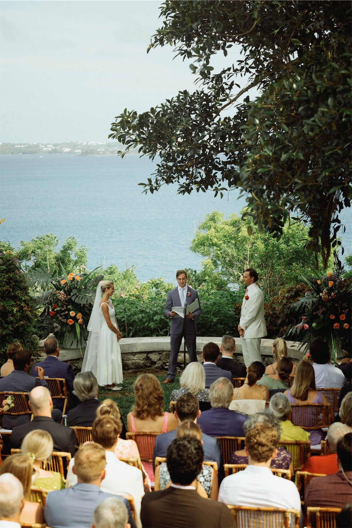 Bride and groom at the altar with seated guests and the ocean beyond