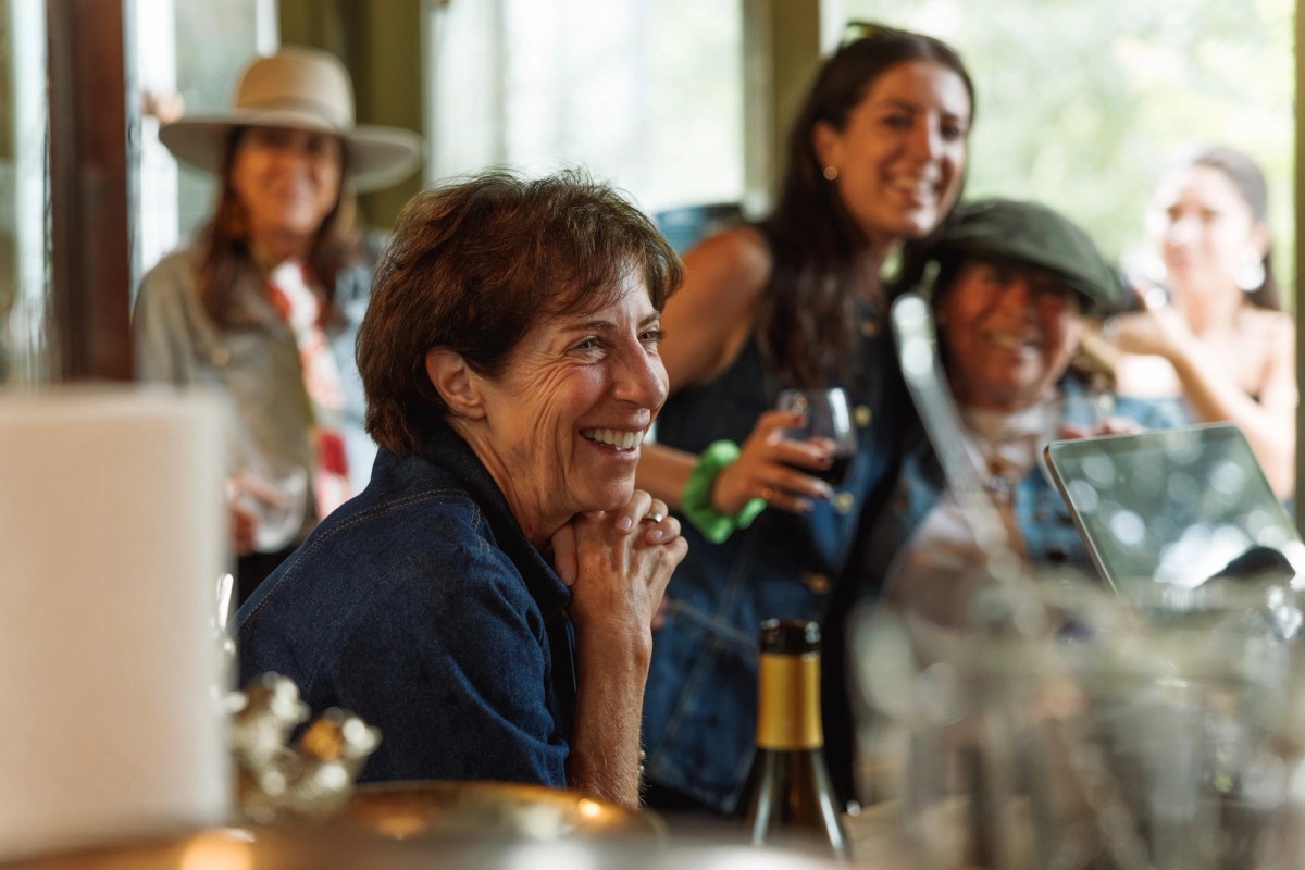 Family smiling around the table with wine at the welcome dinner at a mountain ranch among the aspens
