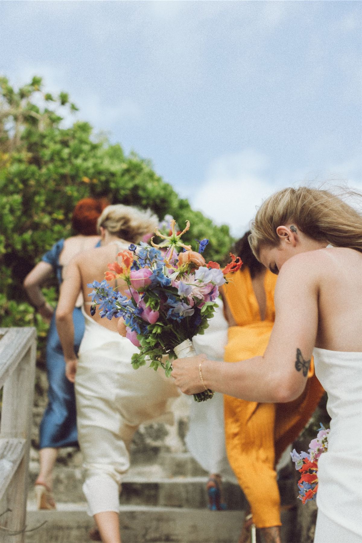 Bride climbing stone steps while a bridesmaid carries her bouquet